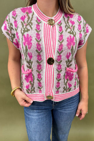 Person wearing a pink floral patterned cardigan with a green background