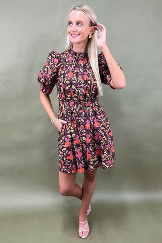 Woman wearing a floral dress against a plain background