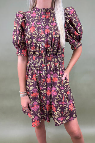 Woman wearing a floral dress with puff sleeves against a plain background