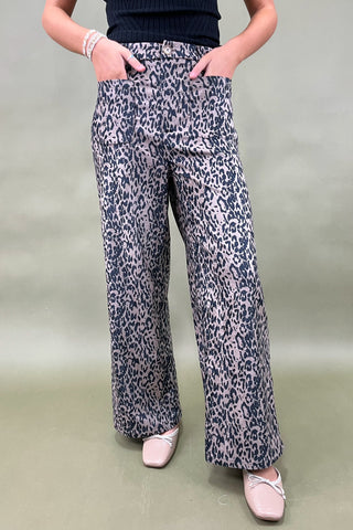 Person wearing leopard print pants on a plain background