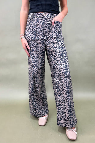 Person wearing leopard print pants on a plain background