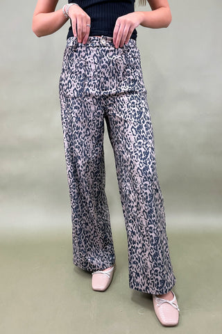 Person wearing leopard print pants on a plain background