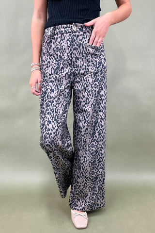 Person wearing leopard print pants on a plain background