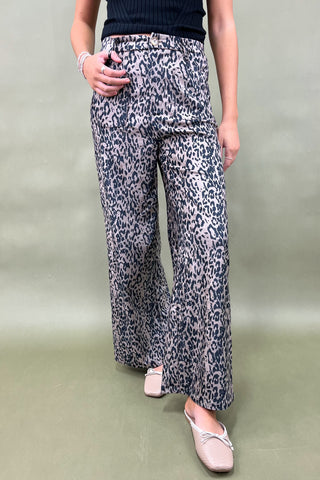 Person wearing leopard print pants on a plain background
