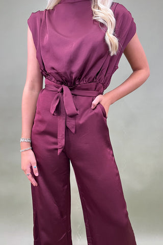 Person wearing a maroon jumpsuit with a plain background