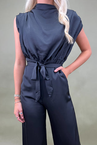 Person wearing a navy blue jumpsuit against a plain background
