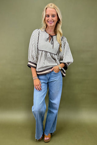 Woman wearing a striped blouse and jeans against a green background