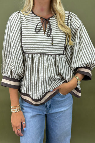 Woman wearing a striped blouse and blue jeans against a green background