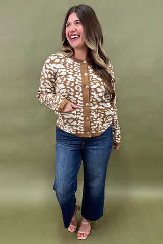 Woman wearing a patterned jacket and jeans on a green background