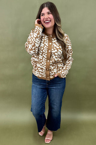 Woman wearing a patterned jacket and jeans against a green background