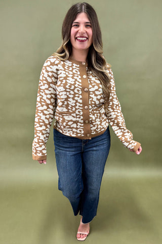 Woman wearing a patterned blouse and jeans against a green background