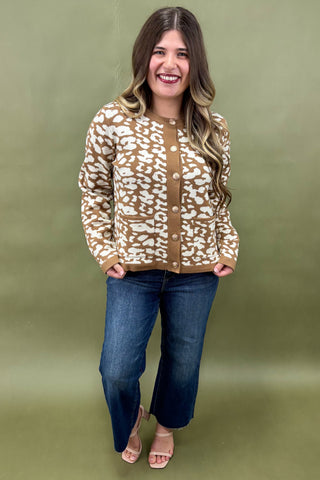Woman wearing a patterned sweater and jeans against a green background