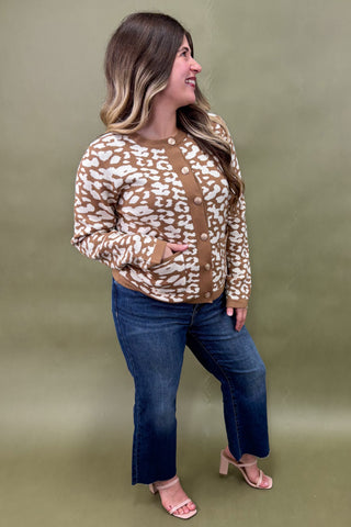 Woman wearing a patterned sweater and jeans against a green background