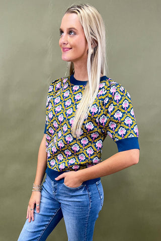 Pair of beige sandals on a woven mat with a plant in the background