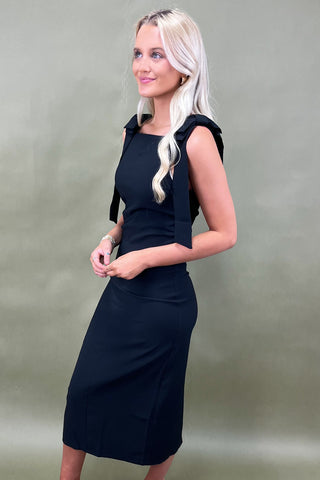 Woman wearing a black dress against a plain background