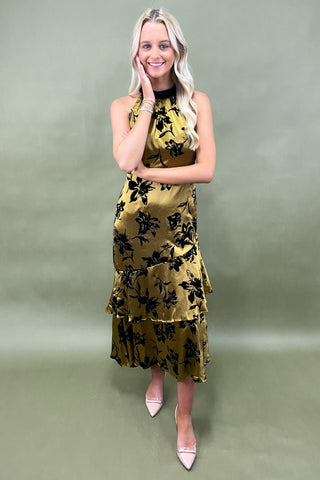 Woman wearing a yellow floral dress against a plain background