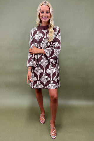 Woman wearing a patterned dress against a green background