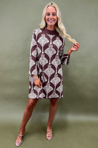 Woman wearing a patterned dress against a green background