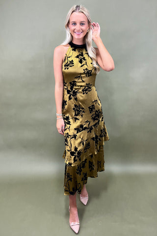 Woman wearing a yellow floral dress against a plain background