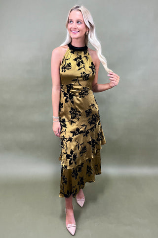 Woman wearing a yellow floral dress against a plain background