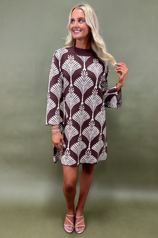 Woman wearing a patterned dress against a plain background