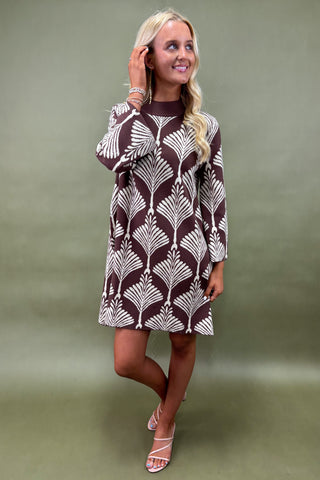 Woman wearing a patterned dress against a green background