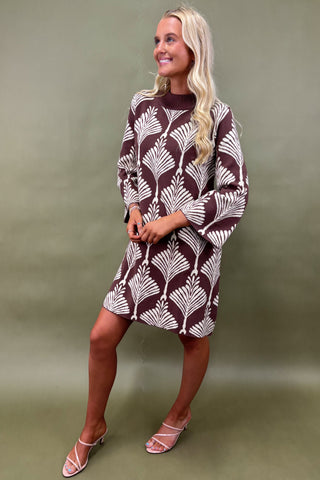 Woman wearing a patterned dress against a green background