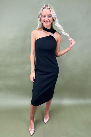 Woman wearing a black one-shoulder dress against a green background