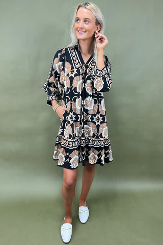 Woman wearing a patterned dress with white shoes on a green background