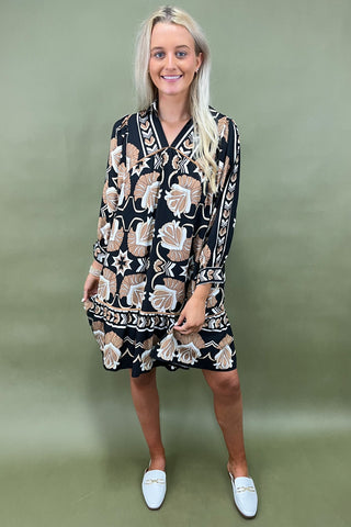 Woman wearing a black patterned dress against a green background