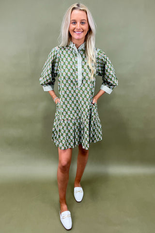 Woman wearing a green patterned dress on an olive green background