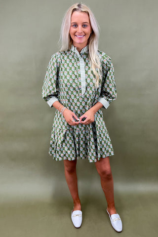 Woman wearing a green patterned dress against a plain background