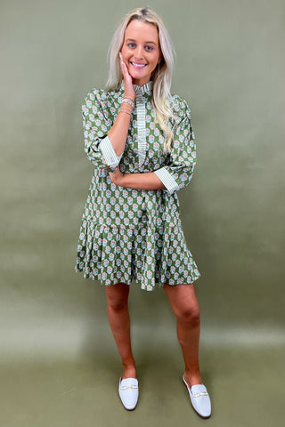 Woman wearing a green floral dress against a plain background