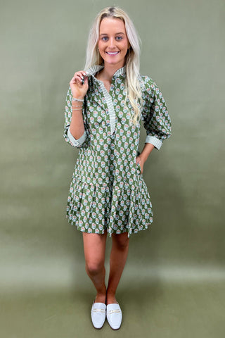 Woman wearing a green floral dress against a plain background