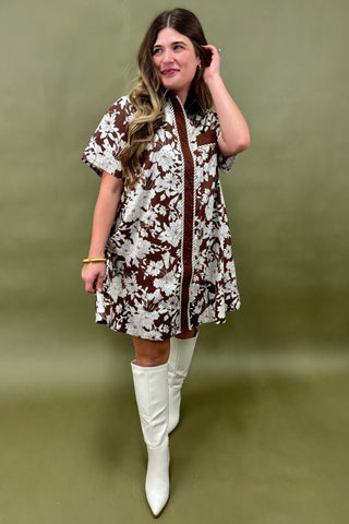 Woman wearing a patterned dress and white boots against a green background