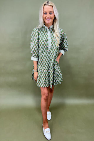 Woman wearing a green patterned dress against a plain background