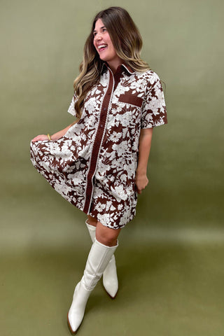 Woman wearing a patterned dress with white knee-high boots on a green background
