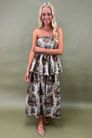 Woman wearing a floral strapless dress against a plain background