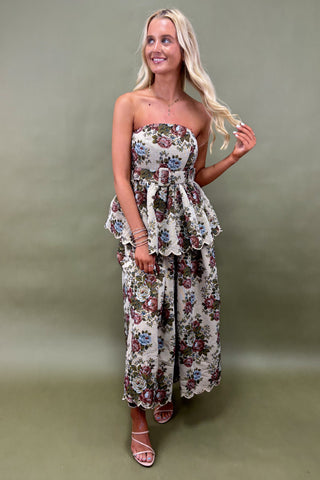 Woman wearing a floral strapless dress against a plain background