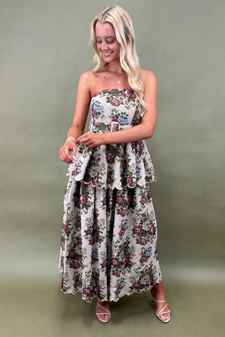 Woman wearing a floral strapless dress against a plain background