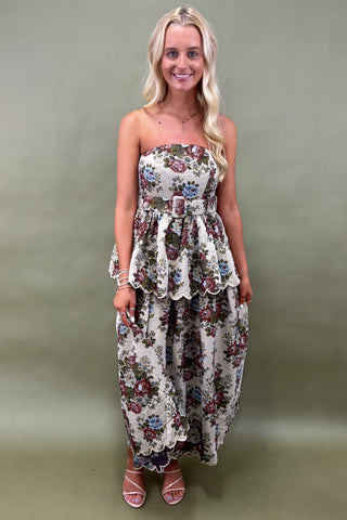 Woman wearing a floral strapless dress against a plain background