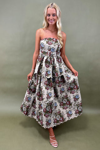 Woman wearing a floral strapless dress against a plain background