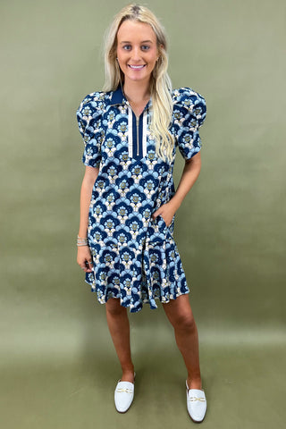 Woman wearing a blue and white patterned dress against a green background