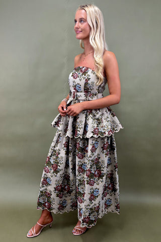 Woman wearing a floral strapless dress against a green background