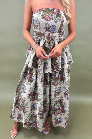 Woman wearing a floral strapless dress against a plain background
