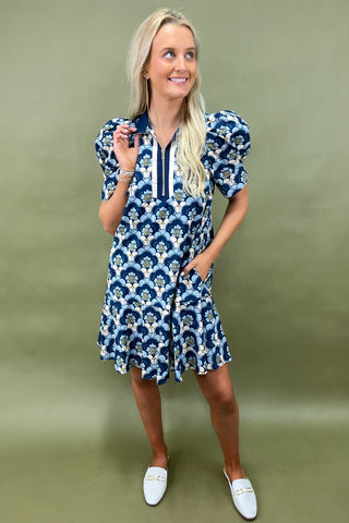Woman wearing a blue and white patterned dress against a green background