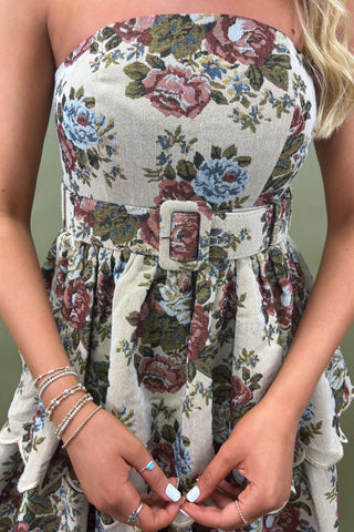 Floral dress with a belt and silver accessories on a neutral background