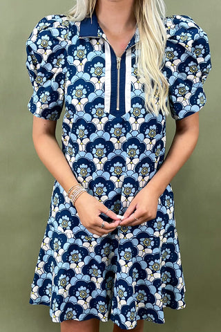 Woman wearing a blue floral dress against a green background