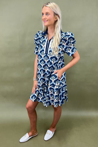 Woman wearing a blue floral dress against a green background