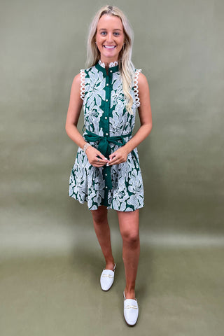 Woman wearing a green and white patterned dress against a plain background